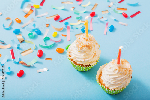 birthday hat with confetti and cupcake on blue paper background