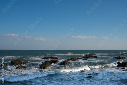 ゴツゴツした岩に打ち寄せる波と青空