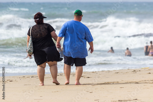 overweight couple walking on the beach