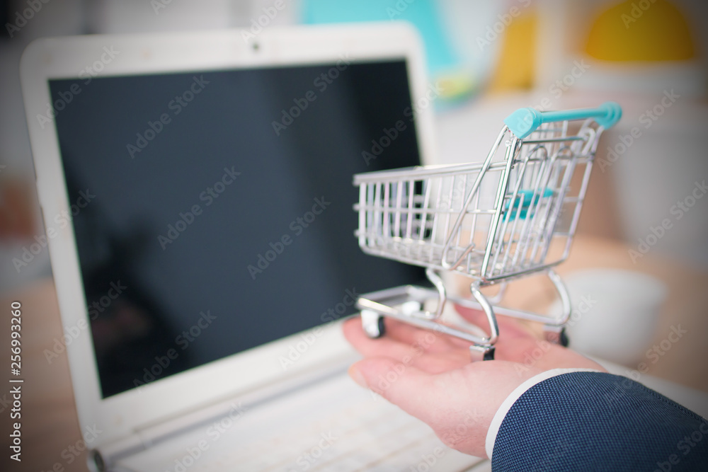 businessman with miniature shopping cart in the office, shopping and sales concept