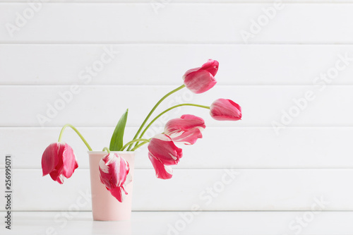 pink tulips in vase on white wooden background