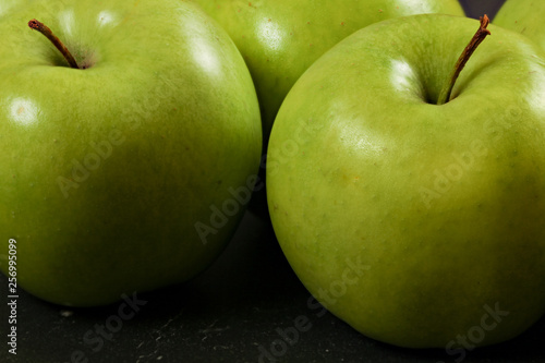 Green apples on black board - closeup photo with detail on skin texture.