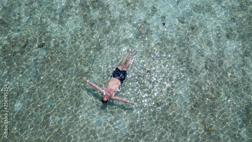 Man floating on the water in blue ocean. Relaxed male on his holidays in the sea View from above. Relax conception