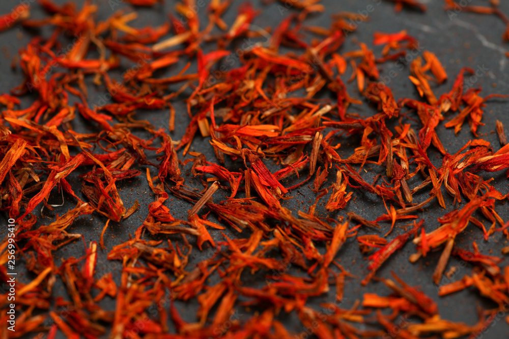 Fototapeta premium Bright red orange dried saffron (Crocus sativus) flowers on black board.