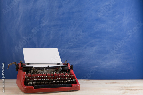writer's workplace - red typewriter on blue blackboard background