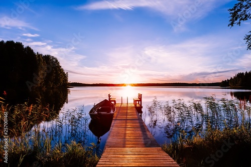 Fototapeta Naklejka Na Ścianę i Meble -  Wooden pier with fishing boat at sunset on a lake in Finland