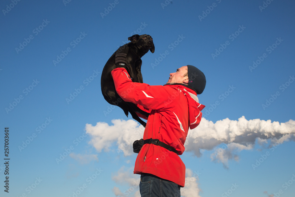 Portrait of happy man holding his friend dog at sunny meadow in winter Portrait of happy man holding his friend dog at sunny meadow in winter