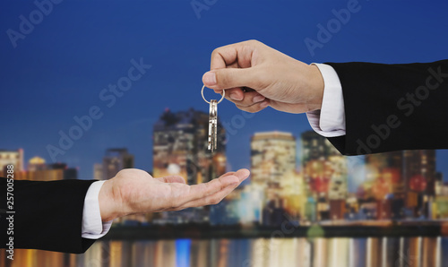 Real estate business, residential rental and investment. Businessman handover keys, with city at night backgrounds