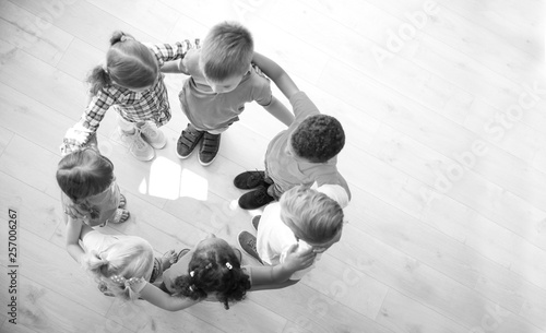 Little children making circle with hands around each other indoors, top view. Unity concept