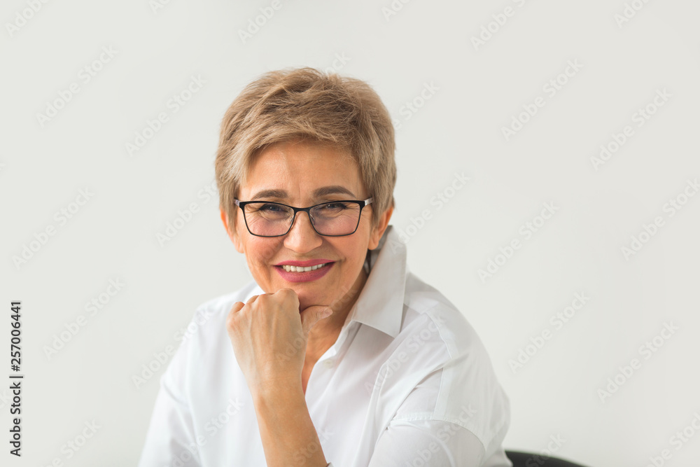 portrait of stylish aged woman with glasses and short haircut on a white background