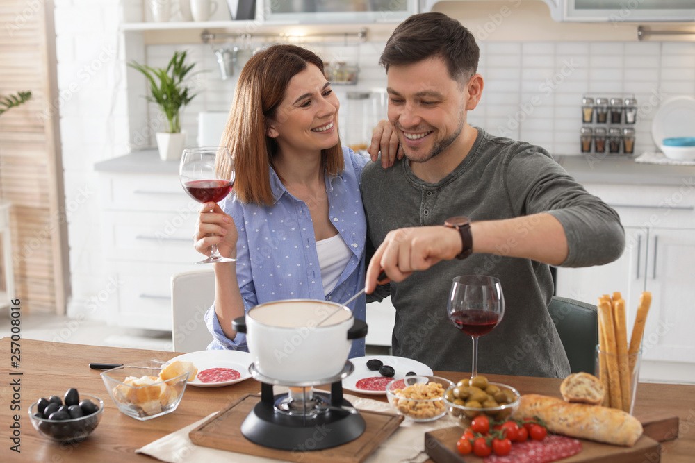 Happy couple enjoying fondue dinner at home Happy couple enjoying fondue dinner at home