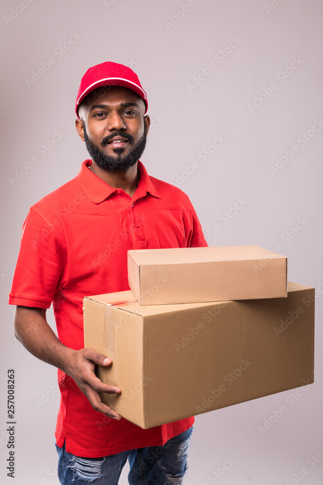 Side view of indian delivery man with box in studio. isolated gray background Side view of indian delivery man with box in studio. isolated gray background