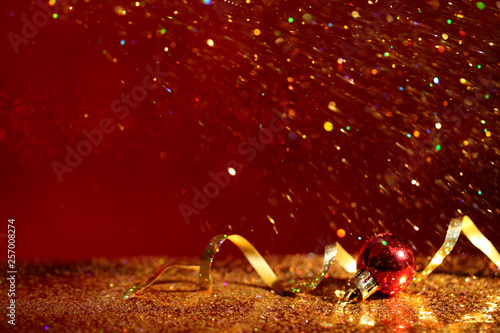 Golden glitter, Christmas ball and streamer against color background. Space for text