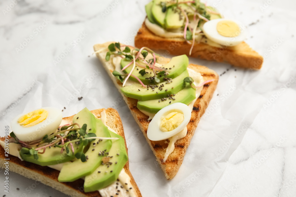 Tasty toasts with avocado, quail eggs and chia seeds on marble background Tasty toasts with avocado, quail eggs and chia seeds on marble background