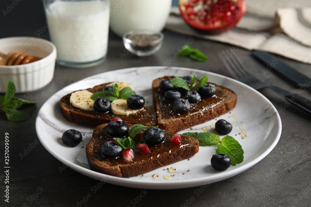 Different toasts with fruits, blueberries, honey and chia seeds on plate