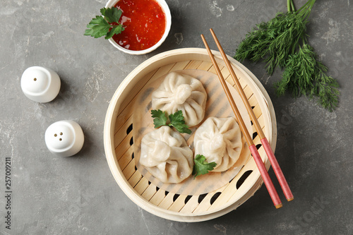 Bamboo steamer with tasty baozi dumplings and chopsticks on table, top view photo