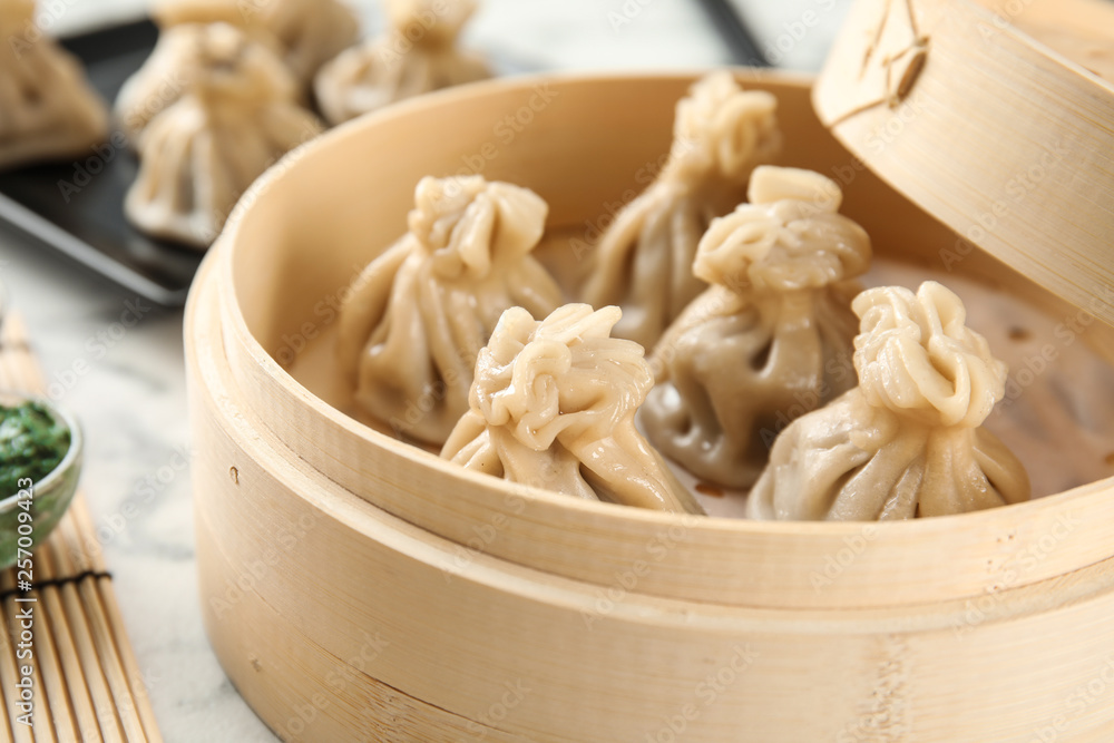 Bamboo steamer with tasty baozi dumplings on table, closeup Bamboo steamer with tasty baozi dumplings on table, closeup