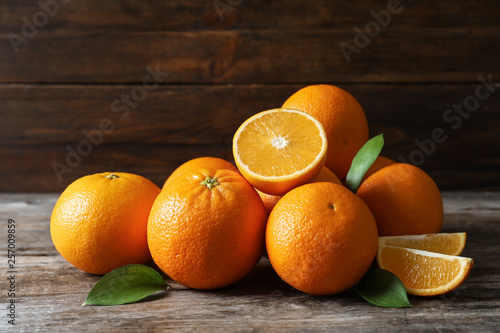Fresh oranges with leaves on wooden table