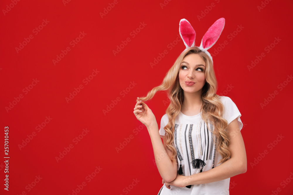 Portrait of beautiful young woman in Easter bunny ears headband on color background, space for text