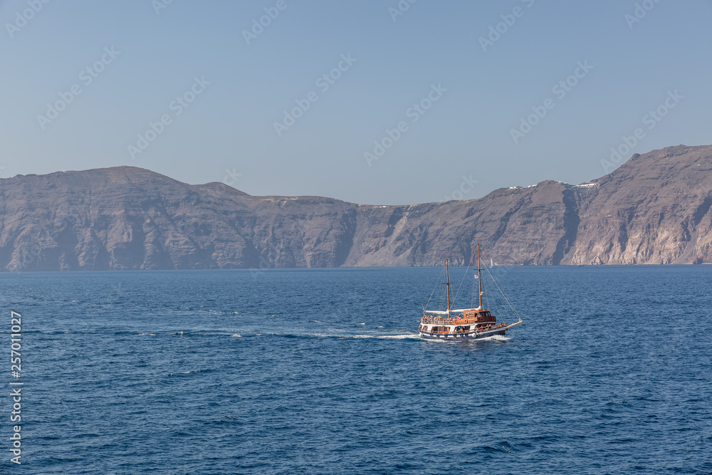 Beautiful view of a nice boat sailing near the island of Santorini in a calm sea