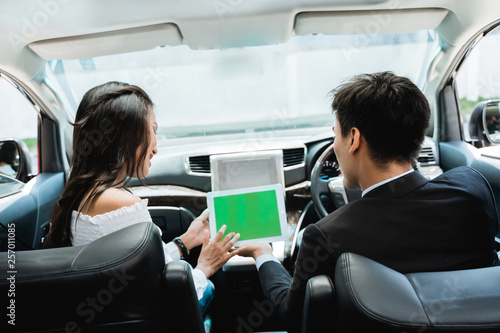 two couple using tablet together while driving a car looking for gps direction