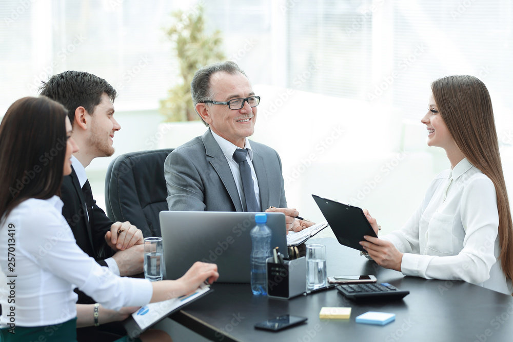 Manager discussing work issues with his assistants behind a Desk Manager discussing work issues with his assistants behind a Desk
