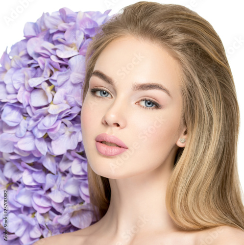 Beautiful young blonde woman with flowers near face