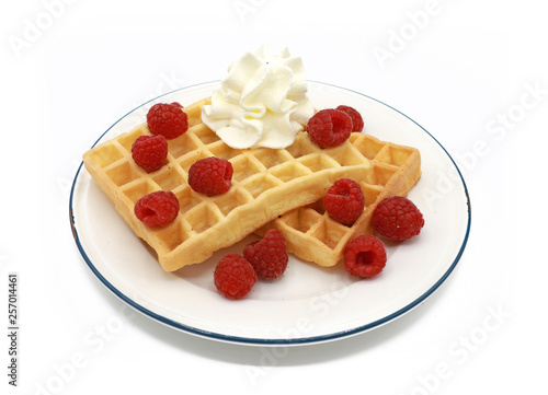  fresh belgian waffles with raspberrys  and whipped cream on a plate isolated on white background