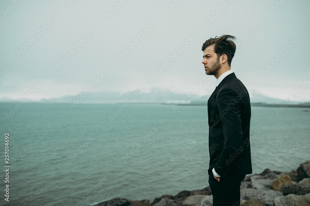 Man in the suit by the sea next to the lighthouse