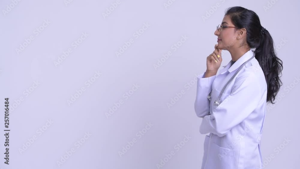 Profile view of young happy Persian woman doctor thinking Profile view of young happy Persian woman doctor thinking