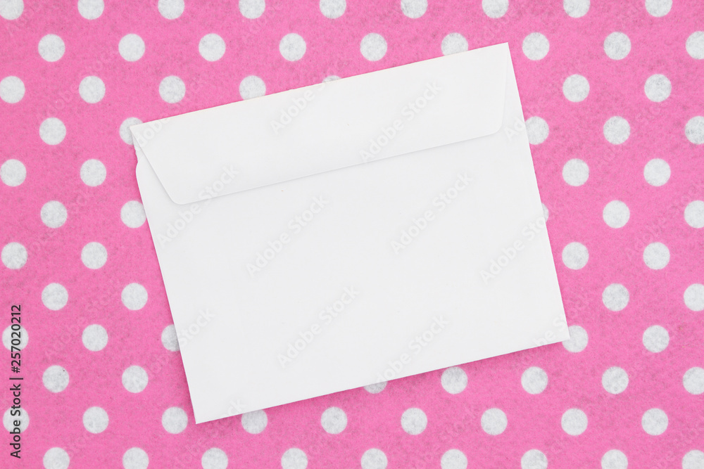 Blank white envelope on pink and white polka dot fabric Blank white envelope on pink and white polka dot fabric