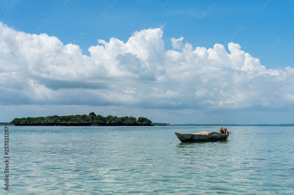 Fisherman fishing and sails on a wooden boat on clear blue water along a tropical exotic beach in Africa. Indian Ocean, Zanzibar Fisherman fishing and sails on a wooden boat on clear blue water along a tropical exotic beach in Africa. Indian Ocean, Zanzibar