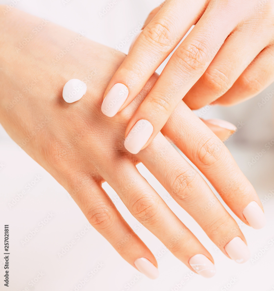 Fototapeta premium Young female hands applying moisturizing cream.