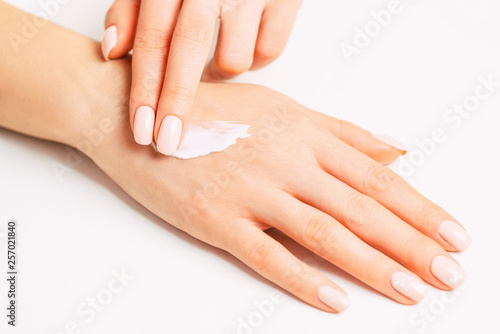 Woman   s hands applying moisturizing skincare cream.
