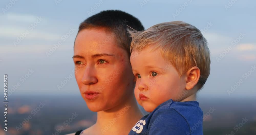 Portrait of pretty smiling woman hugging cute small child looking at beautiful sunrise. Close-up. Portrait of pretty smiling woman hugging cute small child looking at beautiful sunrise. Close-up.