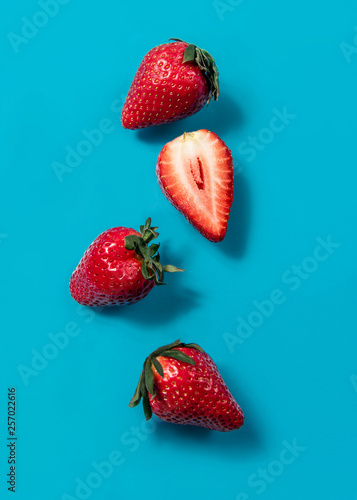 Red strawberry floating on blue background. Minimal food idea concept. Bright colors, flat lay