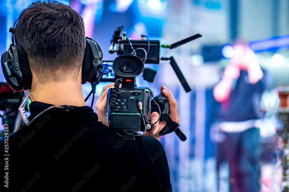Video operator shoots on camera. Video camera with a transmitting device over Wi-Fi. Video production. Videographer in headphones. Video stream Video operator shoots on camera. Video camera with a transmitting device over Wi-Fi. Video production. Videographer in headphones. Video stream