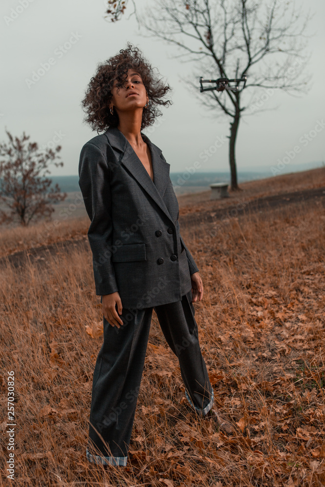 Beautiful girl with curly hair in a stylish suit walks against the backdrop of a beautiful landscape Beautiful girl with curly hair in a stylish suit walks against the backdrop of a beautiful landscape