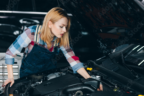 engines trend monitoring. cute blonde learning to fix the car. close up photo. unusual job for women