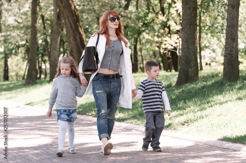 Fototapeta Naklejka Na Ścianę i Meble -  mom with two kids walking in the city Park