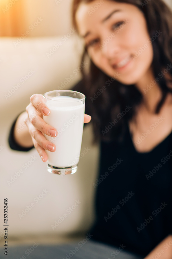 Beautiful young woman with glass of milk at home