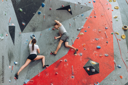 Strong man encouraging and directing woman on the climbing wall. Slim woman moving slowly feeling not confident.copy space