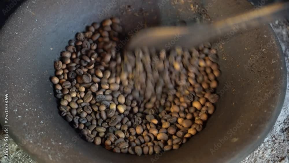 Coffee grains are roasted in an earthenware pot on fire in a local Balinese house, Ubud, island Bali, Indonesia. Roasted coffee beans in a clay pot on the kitchen, close up Coffee grains are roasted in an earthenware pot on fire in a local Balinese house, Ubud, island Bali, Indonesia. Roasted coffee beans in a clay pot on the kitchen, close up