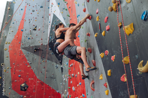 young awesome couple doing aerobic exercise at climbing gym. full length photo. climbing technique, difficulties in climbing