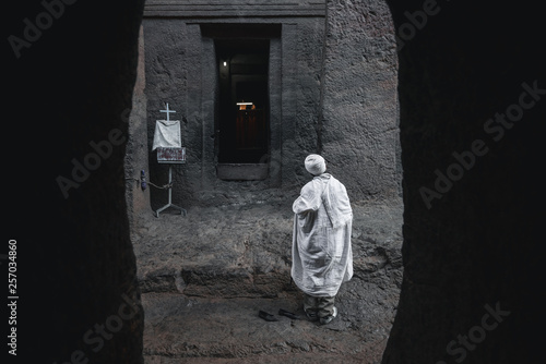 Old priest in white robe with walking stick praying at the  lalibela church in ethiopia  © Vegetation7