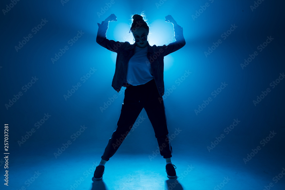 Fototapeta premium Stylish woman dancing solo on hip hop party. Sunglasses, modern black dance wear, neon lights.