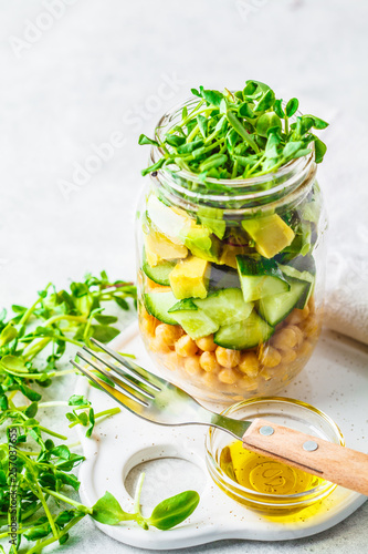 Green salad with chickpeas in a jar, white background, copy space.