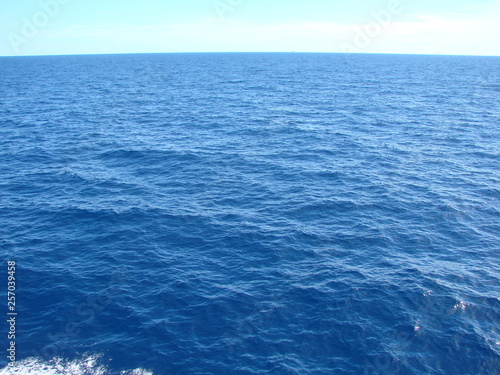 A view from the deck elevation of the ocean liner to the amazing shades of sea blue under the sun rays.