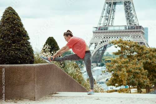 Photography woman jogger against clear view of Eiffel Tower stretching
