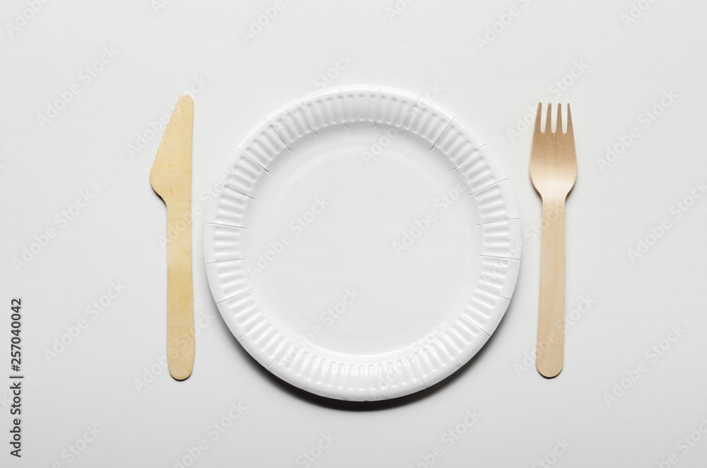 Wooden single use kitchenware and paper plate on white background closeup. Top view Wooden single use kitchenware and paper plate on white background closeup. Top view